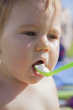 portrait of baby eating from green spoon