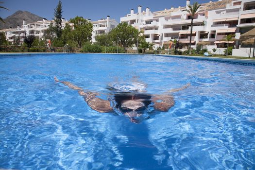 woman with goggles diving breaststroke in a blue pool
