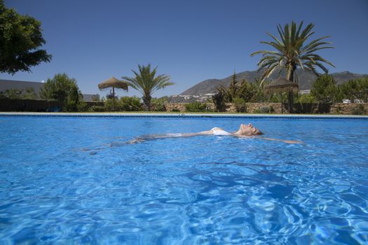 white bikini woman lying on the water in a big blue pool