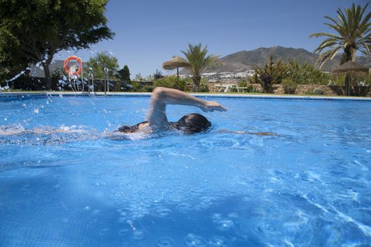 woman swimming crawl in a blue pool