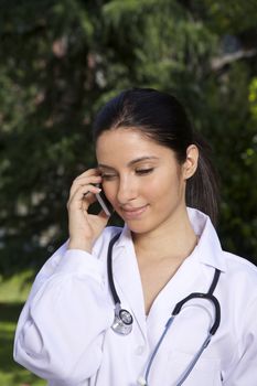 doctor young woman talking mobile over a green trees background
