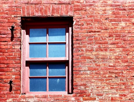 Old window in the middle of an old red brick wall.