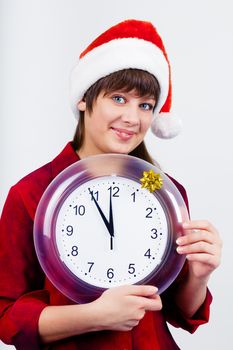 Young blue-eyed beautiful girl in santa hat with clock
