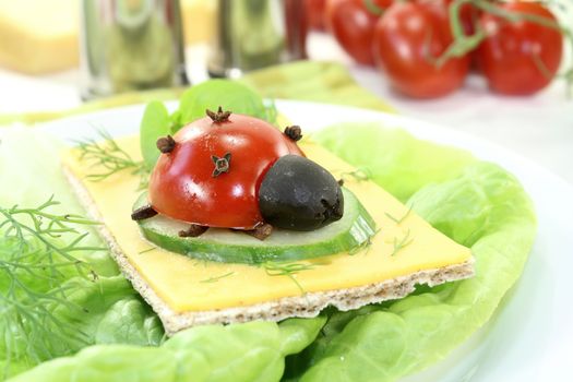 Crispbread with cheese, lettuce and ladybug on a light background