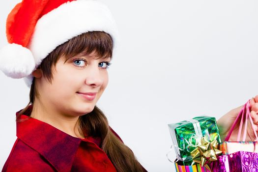 Young blue-eyed beautiful girl in santa hat with presents