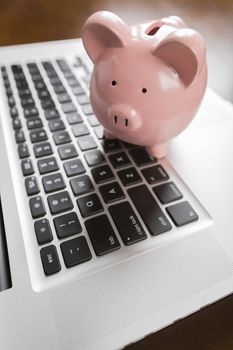 Piggy Bank Resting on Laptop Computer Keyboard.