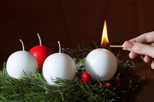 woman's hand lit the first candle of the Advent wreath