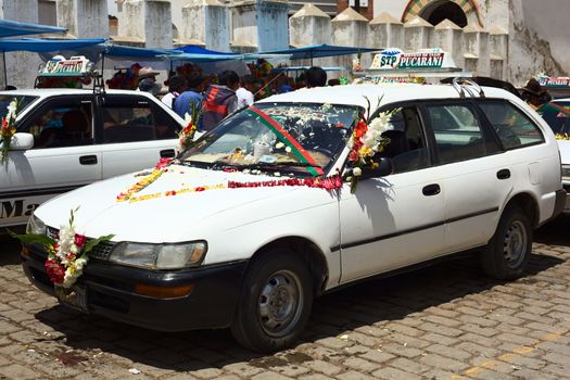 COPACABANA, BOLIVIA - OCTOBER 20, 2014: Decorated taxis standing in line for the blessing in front of the basilica on October 20, 2014 in the small tourist town of Copacabana, Bolivia. Daily many cars, buses and trucks receive blessing from the priest.  