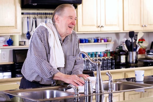 Elderly man washing dishes in kitchen