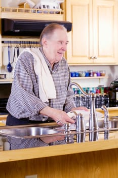 Elderly man washing dishes in kitchen