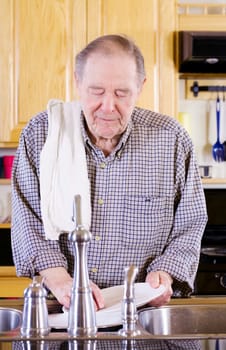 Elderly man washing dishes in kitchen