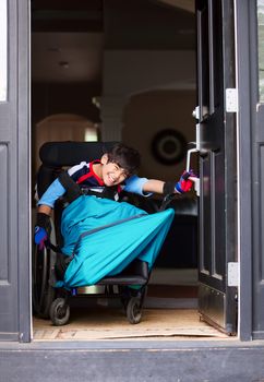 Smiling disabled boy in wheelchair opening front door