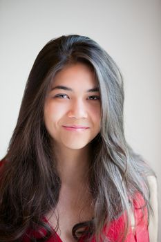 Beautiful biracial teen girl in red dress smiling into  camera