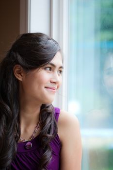 Beautiful biracial young woman smiling, looking out window