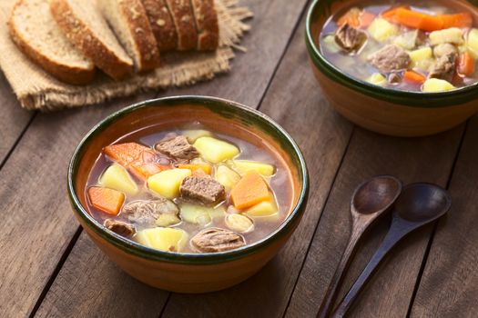 Two bowls of traditional Hungarian soup called Gulyasleves made of beef, potato, carrot, onion, csipetke (homemade pasta) and seasoned with salt and paprika (Selective Focus, Focus in the middle of the soup in the first bowl)