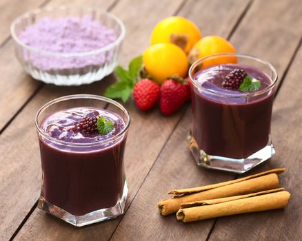 Ecuadorian traditional thick drink called Colada Morada, prepared by cooking purple corn flour and different fruits (for example strawberry, pineapple, naranjilla, grape, babaco, blackberry, etc) and seasoned with panela (cane sugar), cinnamon, allspice and cloves (Selective Focus, Focus on the blackberry on the left drink)