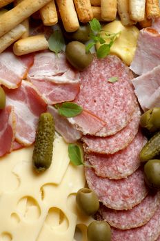 Background of Delicious Emmental Cheese, Smoked Meat and Smoked Salami with Gherkins,Green Olives and Bread Sticks closeup