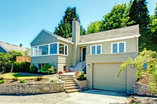 House exterior in clapboard siding. House with garage, driveway and front yard landscape