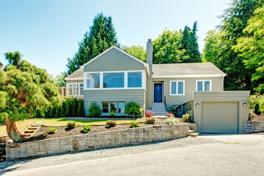 House exterior in clapboard siding. House with garage, driveway and front yard landscape