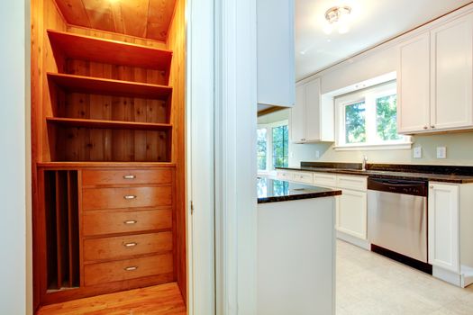 White ktichen room with wooden closet. Small closet with storage shelves and drawers