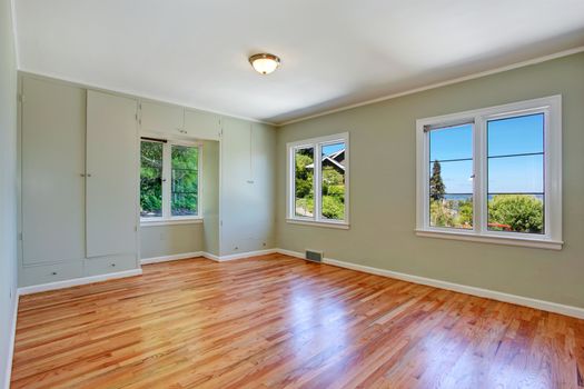 Empty master bedroom interior with windows, hardwood floor and built in wardrobe