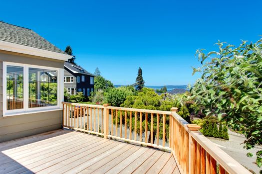 Wooden walkout deck with railings. Deck overlooking driveway and neighborhood