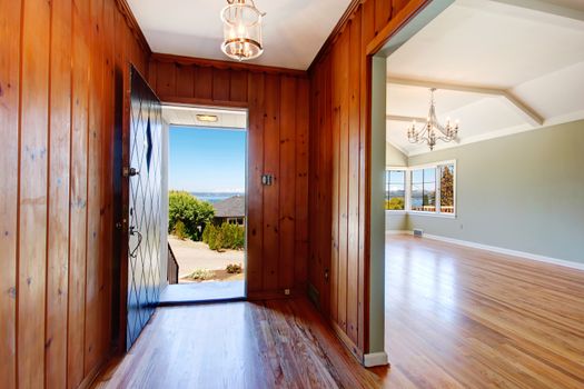 Empty house interior. Entrance hallway with wood plank paneled walls and hardwood floor