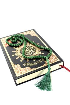slammed Quran with green rosary before light background