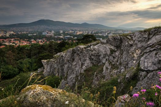 Village under a Hill at Sunset with Rocks in Foreground.