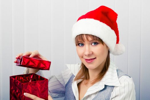 Attractive girl in the office in Santa hats with a gift