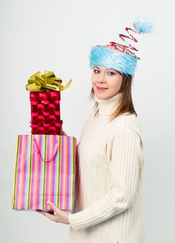 Attractive happy girl in an unusual Christmas hat with gift boxes