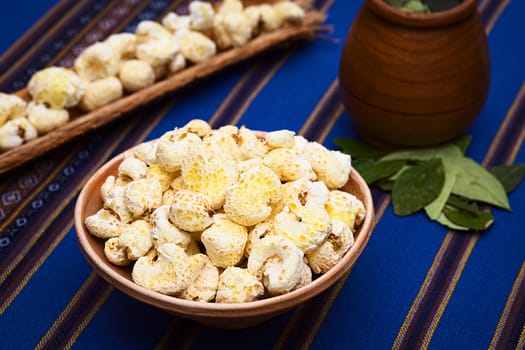 Sweetened popped white corn called Pasancalla eaten as snack in Bolivia served in a clay bowl with coca tea in the back, photographed with natural light (Selective Focus, Focus in the middle of the snack) 
   