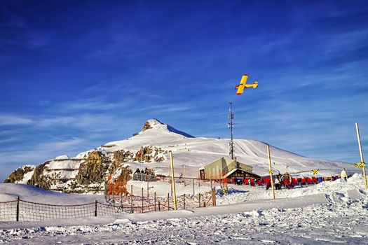 Yellow airplane flying over alpine resort in swiss alps in winter