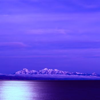 Lake Titicaca and the snow-capped mountains of the Andes photographed from the Isla del Sol (Island of the Sun) at night with the full moon shining 