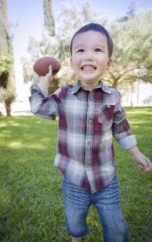 Cute Young Mixed Race Boy Playing Football Outside At The Park.