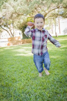 Cute Young Mixed Race Boy Playing Football Outside At The Park.