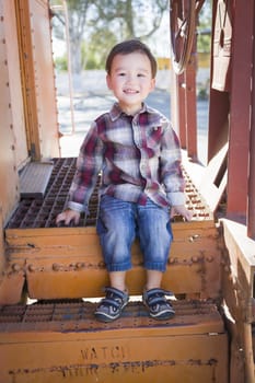 Cute Young Mixed Race Boy Having Fun Outside Sitting on Railroad Car Steps.