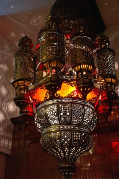 Typical handmade Moroccan Arabic lantern lamp illuminating patterns of light on the wall