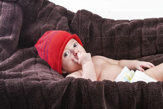 Surprising baby boy over brown blanket on white background