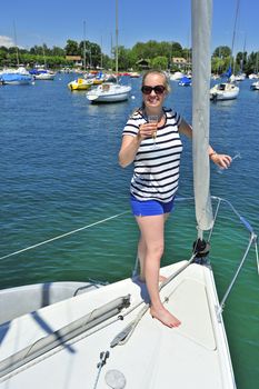 A young woman raises a glass in toast at the bow of a yacht