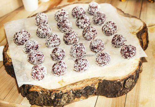 Rum balls in coconut on a wooden plate