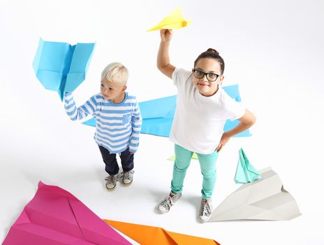 Siblings, a girl and a boy throwing paper airplane