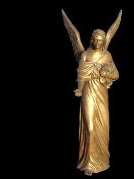 Golden sculpture of an angel. She offers flowers. Isolated on black background