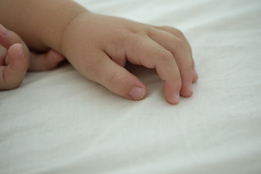 hands of a sleeping baby, white besheet and backround