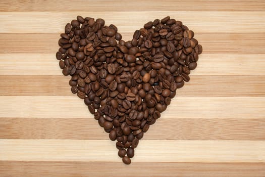 Heart of coffee beans on the wooden board.