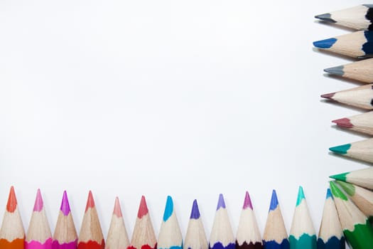 Wooden colored pencils as frame on the white background.