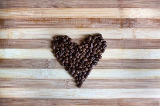 Heart of coffee beans on the wooden board