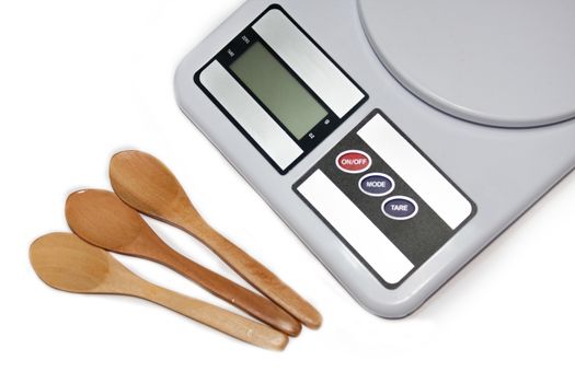 Digital kitchen scale and wooden spoons on the white background.