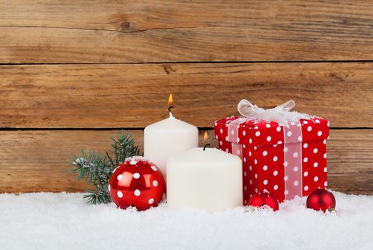 christmas red gift, candle with snow, on wooden background