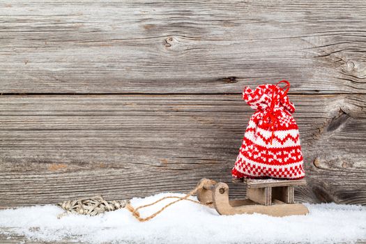 red bag on old rustic wooden sledge, over wooden background